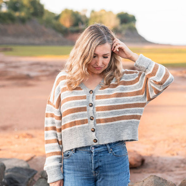 Dayna Manning is shown on a beach. She wears a striped cardigan.